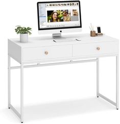 a white desk with a computer on top of it and a potted plant next to it