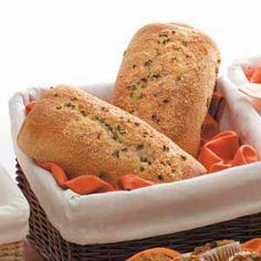 two loaves of bread sitting in a basket next to some carrots and muffins