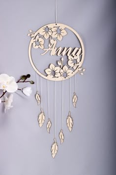 a wooden dream catcher with flowers hanging from it's sides next to a white flower