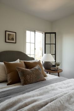 a bedroom with a bed, two lamps and pictures on the wall