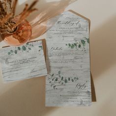 two pieces of paper sitting on top of each other next to a vase filled with flowers