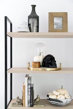 a shelf with books and other items on it, including an eggplant in a bowl