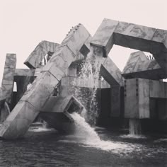 a black and white photo of an art sculpture with water pouring out of it's sides