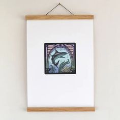 a painting hanging on the wall with a dolphin in it's mouth and fish swimming below