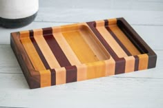 two wooden trays sitting next to each other on a white table with a vase in the background