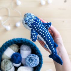 a hand holding a blue and white knitted toy