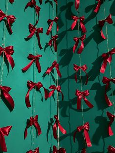 red bows hanging from strings on a green wall next to a blue wall with shadows