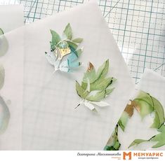 two pieces of paper with leaves on them next to some scissors and cutting mat papers