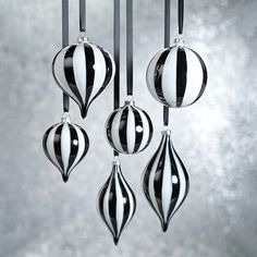 three black and white ornaments hanging from a metal rod in front of a gray background