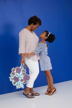 a mother and daughter are posing for a photo in front of a blue wall with flowers on it