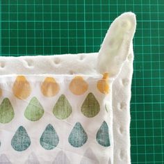 a close up of a piece of cloth on a cutting board with green and yellow drops