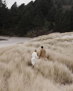 two people are walking through the tall grass