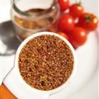 a white plate topped with a bowl filled with brown stuff next to tomatoes and other vegetables