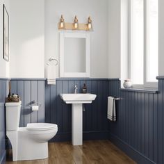 a white toilet sitting next to a sink in a bathroom under a window with wooden floors