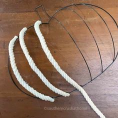 three pieces of white rope sitting on top of a wooden table next to a wire heart