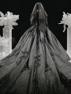 a black and white photo of a woman in a wedding dress with an elaborate veil