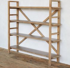 a wooden shelf sitting on top of a wooden floor next to a wall with white walls