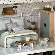 a dollhouse bedroom with white furniture and accessories on the shelves, including a bed