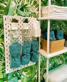 towels and other items are displayed on shelves in a tropical - themed bathroom with palm leaves