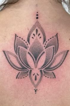 the back of a woman's neck with a lotus tattoo on it, and an intricate