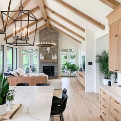 a large open concept kitchen and living room with wood beams on the ceiling, hardwood flooring