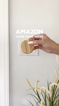 a person holding a wooden object in front of a white wall with the words amazon on it