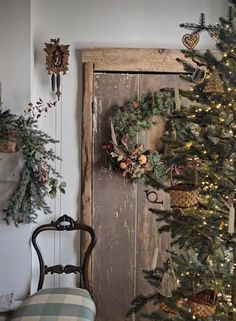 a christmas tree is next to a door with wreaths on it and a chair