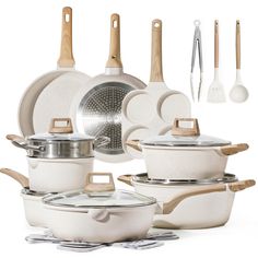 an assortment of white pots and pans with wooden spoons, spatulas and utensils