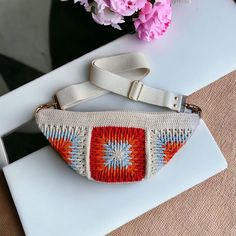 a white purse sitting on top of a table next to a vase filled with flowers