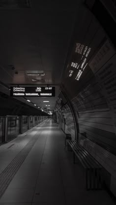 an empty subway station with benches and signs on the walls in black and white colors