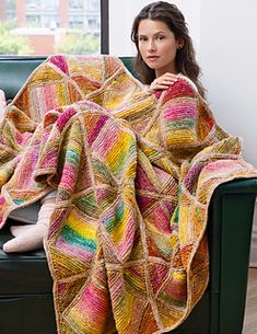 a woman sitting on a couch with a colorful blanket