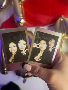 two women are holding up polaroids in front of them