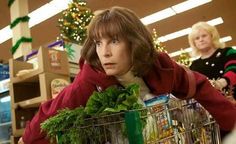 a woman is pushing a shopping cart full of groceries in a grocery store while another woman looks on