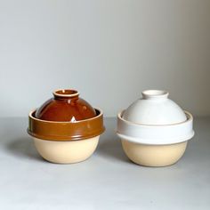 two brown and white bowls sitting next to each other on top of a gray table