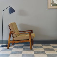 a chair and lamp on a checkered floor in front of a gray painted wall