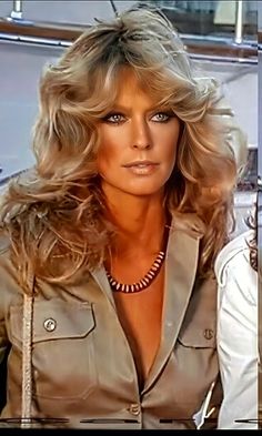 a woman with blonde hair wearing a tan jacket