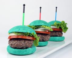 three hamburgers with lettuce and tomatoes on them