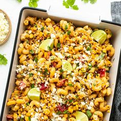 a casserole dish filled with macaroni salad and topped with lime wedges