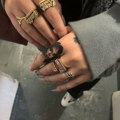 two people wearing rings with tattoos on their fingers and one holding the other hand out