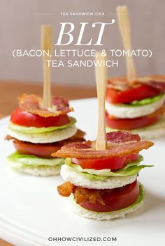 a white plate topped with mini sandwiches covered in lettuce and tomato toppings