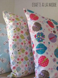 three pillows with different designs on them, one is blue and the other is pink