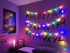 a bedroom decorated in purple and black with colorful lights on the wall above it is a bed