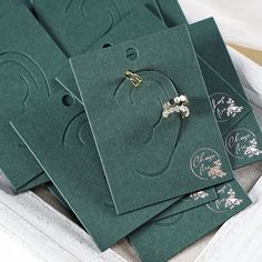 several green envelopes with gold accents are sitting in a white box on the table