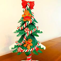 a small christmas tree made out of candy canes and gingerbreads on a wooden table