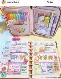 an open planner book sitting on top of a table next to a pink bag filled with pens