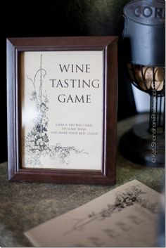 a framed wine tasting game sitting on top of a table next to a cup and book