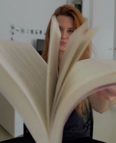 a woman sitting at a table reading a book