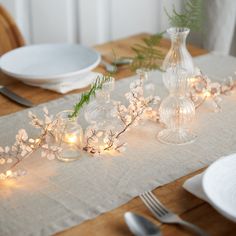 the table is set with candles, plates and flowers in glass vases on it