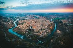 an aerial view of a city and its surrounding river at sunset or sunrise, taken from above