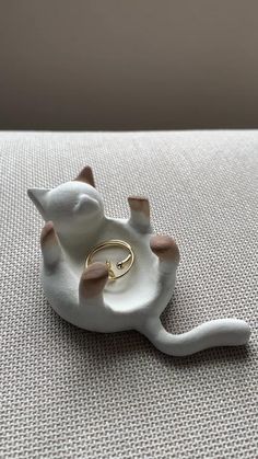 a white ceramic cat ring holder sitting on top of a table